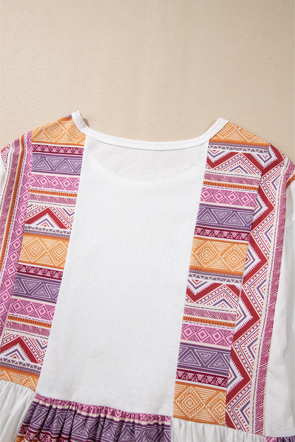 Blusa tipo túnica blanca de manga larga, corte babydoll y estilo occidental, con diseño de retazos (patchwork), estampado azteca y volantes.