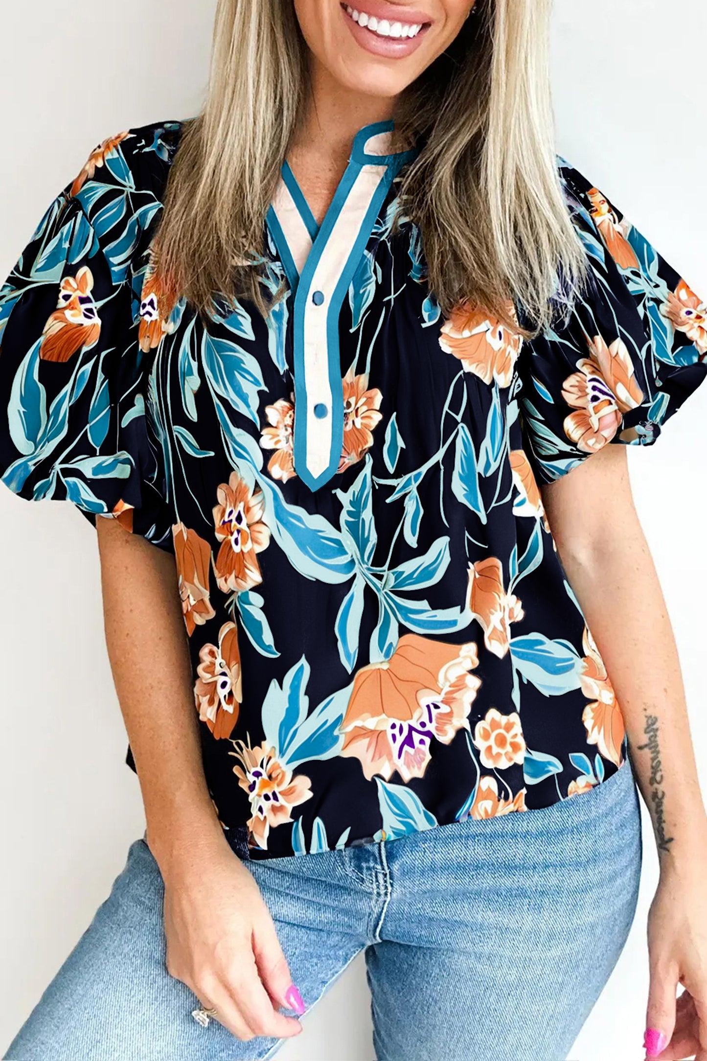 Blusa negra con estampado floral, mangas cortas abullonadas, botones y cuello con muesca