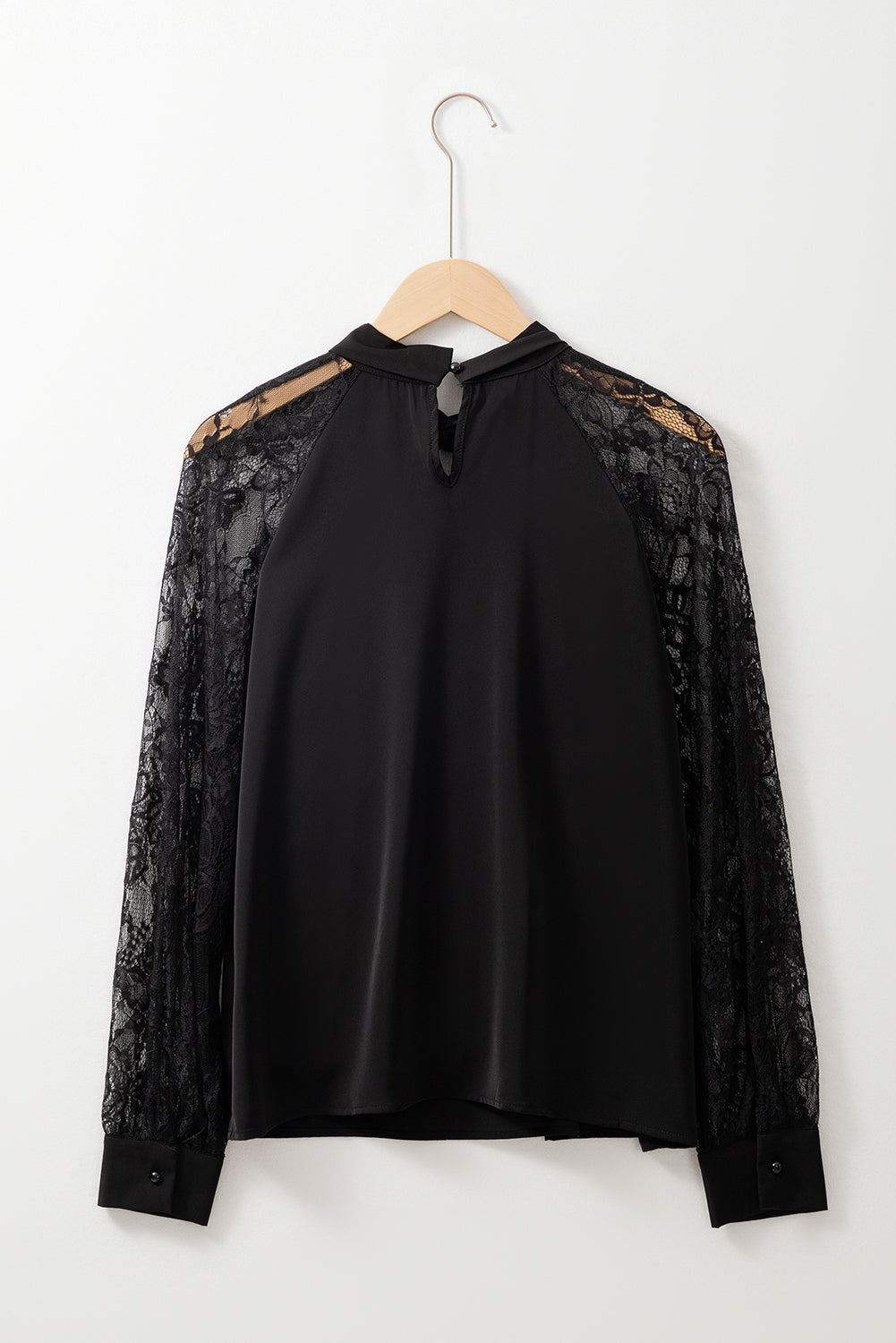 Blusa negra de encaje floral con manga raglán y abertura en el cuello